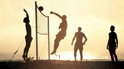 Beachvolleyballspieler bei Sonnenuntergang.