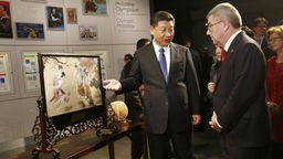 Der chinesische Präsident Xi Jinping und der Präsident des Internationalen Olympischen Komittees Thomas Bach vor einem Bild, das das Spiel Cuju zeigt.