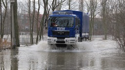 Ein THW-Einsatzfahrzeug fährt durch Wasser. 