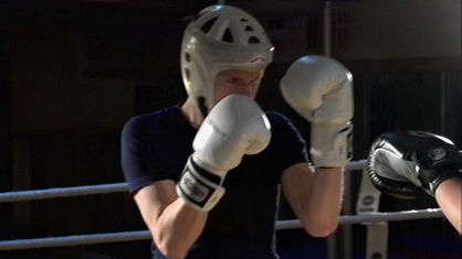 Johannes mit Schutzhelm und Boxhandschuhen bei Kampf.