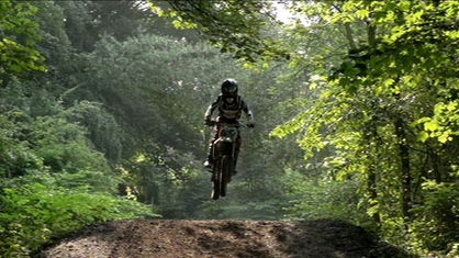 Motorrad auf Waldweg im Sprung.