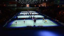 Mehrere Badmintonfelder bei Wettkampf in einer Halle.