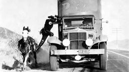 Schwarz-weiß Foto aus Film: Yakima Canutt springt von einem Pferd auf einen fahrenden Wagen.