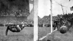 Schwarz-weiß Foto: Torhüter springt vergeblich nach dem Ball, der ins Tor fliegt.