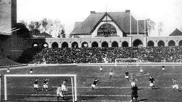 Schwarz-weiß Foto zeigt eine Spielszene während des olympischen Fußballturniers 1912 in Stockholm.
