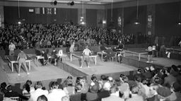 Schwarz-Weiß-Foto: Tischtennisspieler vor Publikum in einer Halle