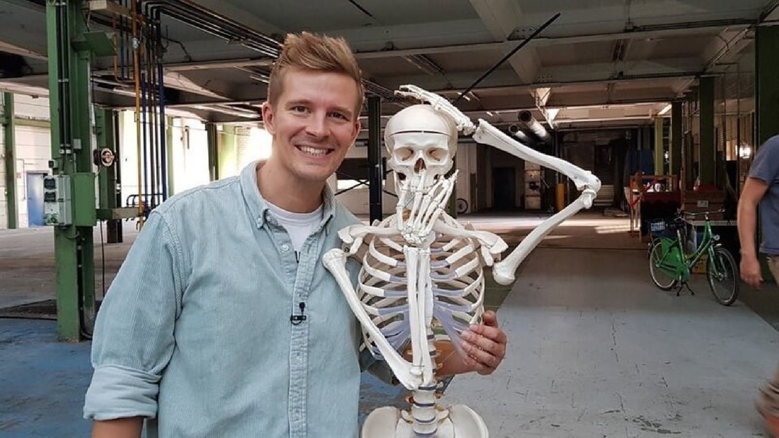 Ein Mitarbeiter vom Läuft-Team legt seinen Arm auf die Schulter von einem Skelett.