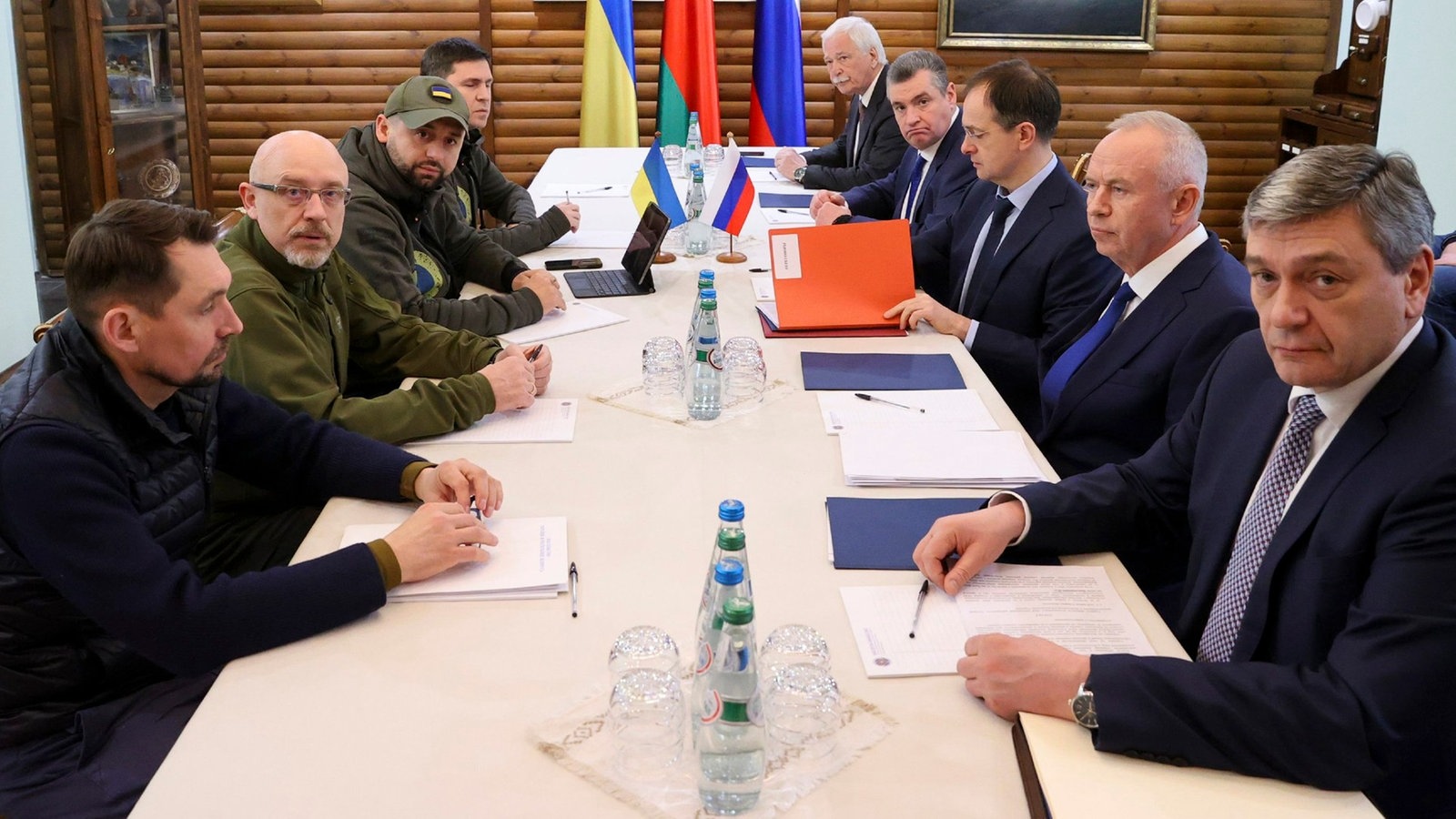 Ukrainische und russische Verhandlungsdelegation sitzen sich an einem Tisch gegenüber.
