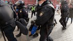 Russische Polizisten tragen Demonstranten.