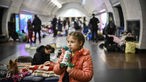 Mädchen steht in U-Bahnstation, in der Flüchtlinge Schutz suchen und trinkt an Trinkflasche.
