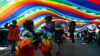 Bei einer Demonstration in Rom spielen Kinder unter einem riesigen Regenbogenbanner.