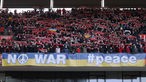 Beim Bundesligaspiel Köln gegen Hoffenheim am 6. März 2022 zeigen Zuschauer ein Transparent mit der Aufschrift "No war, #peace".