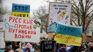 Plakate in russischer und deutscher Sprache gegen den Krieg in der Ukraine auf einer Demonstration in Berlin.