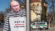 Eine Putin-Pappfigur mit einem Plakat mit der Aufschrift "Putin vor Gericht in Den Haag" steht vor dem Russischen Generalkonsulat in München.