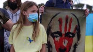 Eine junge Frau mit einem Plakat, das einen roten Handabdruck auf dem Gesicht des russischen Präsidenten Putin zeigt in Nicosia, Zypern.