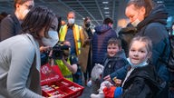 Außenministerin Annalena Baerbock mit Maske bietet geflüchteten ukrainischen Kindern Süßigkeiten an.