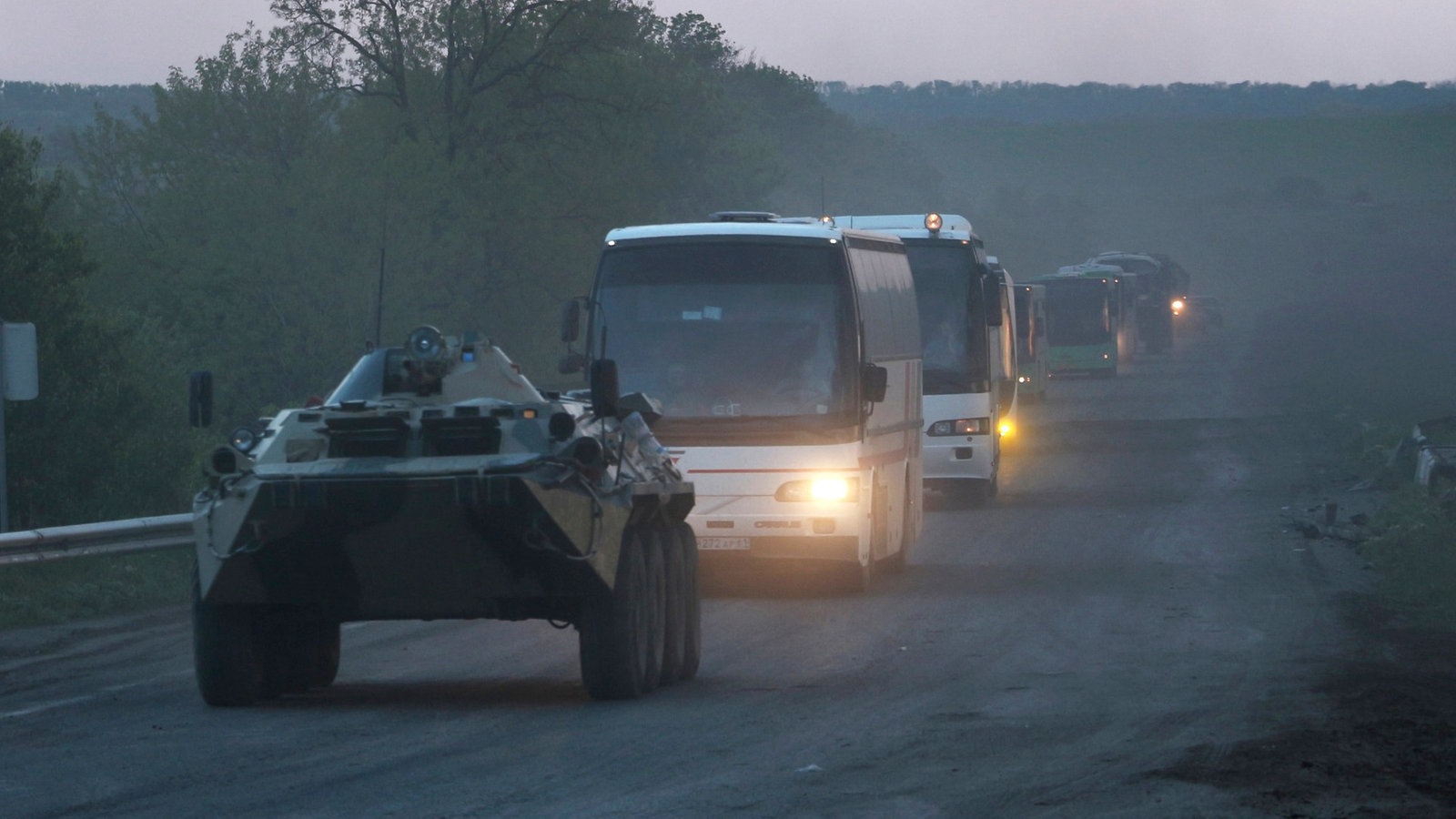 Militärfahrzeug vor einem Bus-Konvoi.