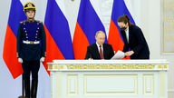Präsident Putin sitzt an Schreibtisch und unterzeichnet das Gesetz zur Annexion ukrainischer Gebiete.