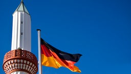 Minarett und wehende Deutschlandflagge.
