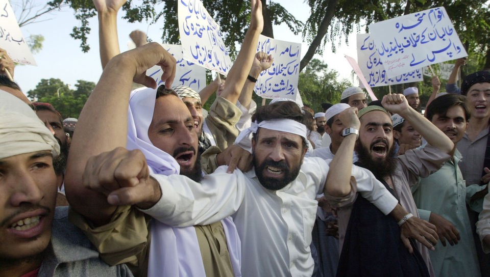 Taliban-Anhänger demonstrieren gegen möglich US-Angriffe und halten Schilder mit arabischer Schrift in Händen