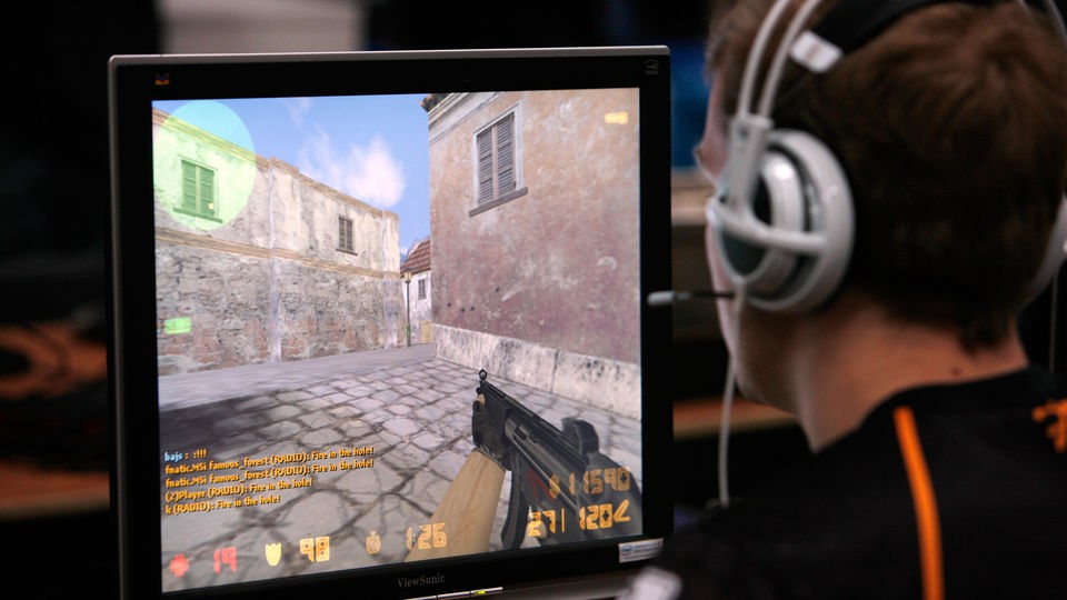 Ein Jugendlicher sitzt vor einem Computermonitor, auf dem ein Gewalt-Spiel zu sehen ist