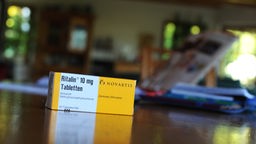 Eine Schachtel mit einem Medikament zur Behandlung von ADHS steht auf einem Tisch. 