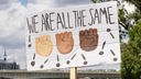 Plakat bei Demonstration zeigt drei Fäuste in unterschiedlichen Hautfarben und Schriftzug 'we are all the same' (wir sind alle gleich).