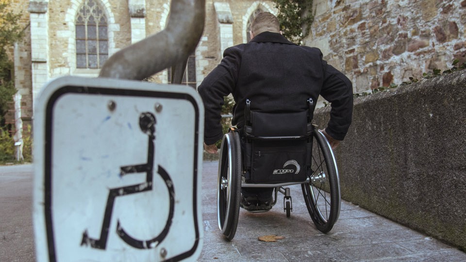 Ein Rollstuhlfahrer fährt eine Rampe hinunter.