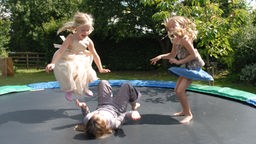 Drei Mädchen springen auf Trampolin.