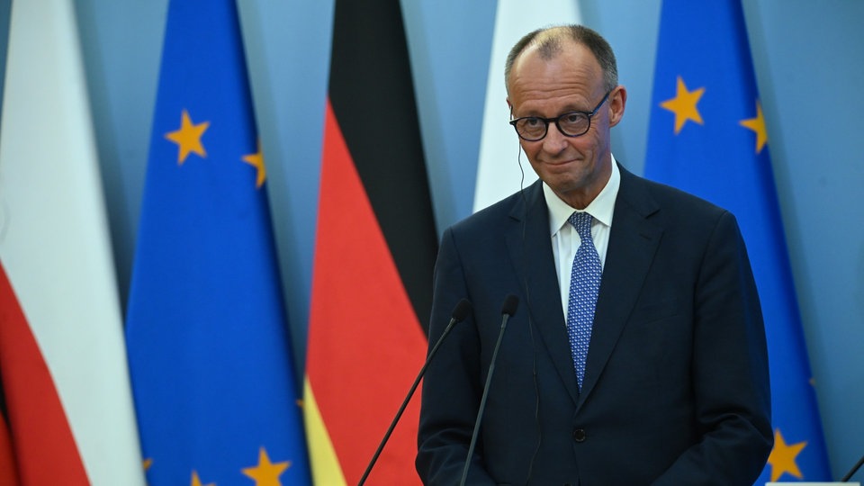 Bundeskanzler Friedrich Merz steht an Rednerpult vor polnischen, europäischen und deutschen Flaggen. | Bildquelle: ddp/Aleksy Witwicki Bundeskanzler Friedrich Merz steht an Rednerpult vor polnischen, europäischen und deutschen Flaggen.