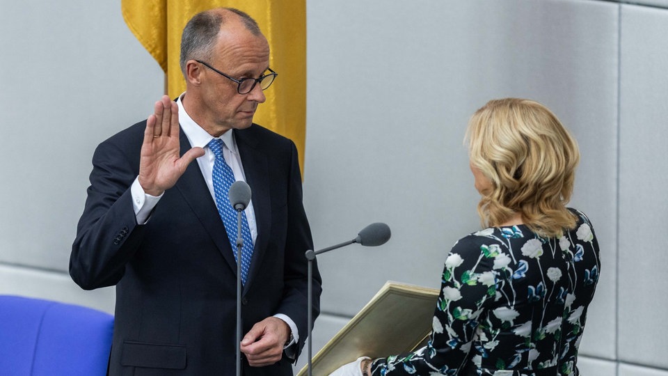 Bundeskanzler Friedrich Merz leistet seinen Amtseid. Rechts steht die Bundestagspräsidentin Julia Kloeckner.