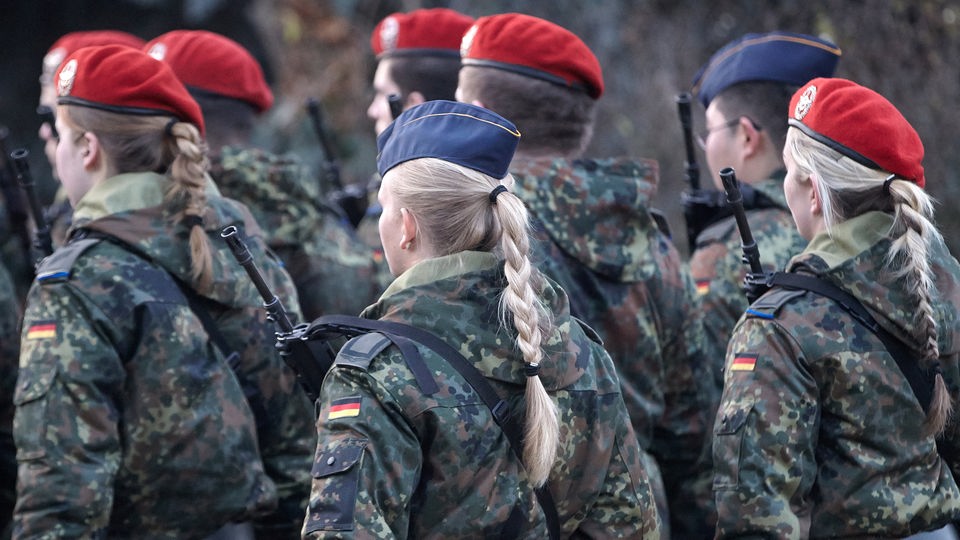 Eine Gruppe Soldaten von hinten, unter ihnen mehrere Frauen mit Zöpfen.