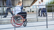 Gehbehinderte Frau im Rollstuhl auf einer Rampe.