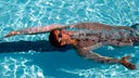 Schwimmer in Haifischhaut-Schwimmanzug beim Rückenschwimmen.