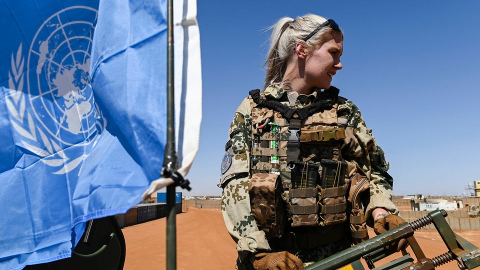 Deutsche Soldatin bei Auslandseinsatz neben Fahne der UNO.