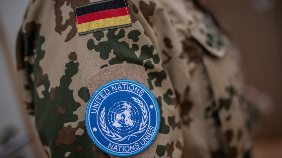 Deutschlandfahne und UN-Logo auf einer Soldatenuniform.