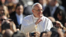 Papst Franziskus winkend in Menschenmenge.