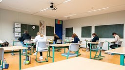 Schülerinnen und Schüler schreiben Abiturprüfung.