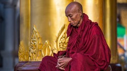 Buddhistischer Mönch meditiert in einem dunklen Raum