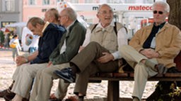 Fünf ältere Männer sitzen auf einer Bank.