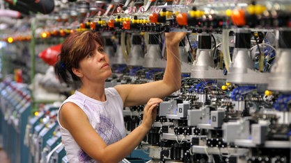 Arbeiterin kontrolliert Maschine.