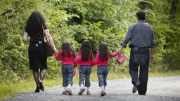 Eine Familie von hinten beim Spaziergang: Mutter, Zwillinge und Vater.