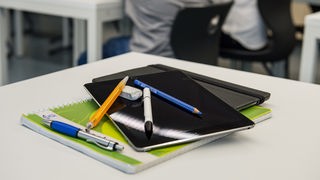 Stifte liegen auf Tablets und Schulheft.