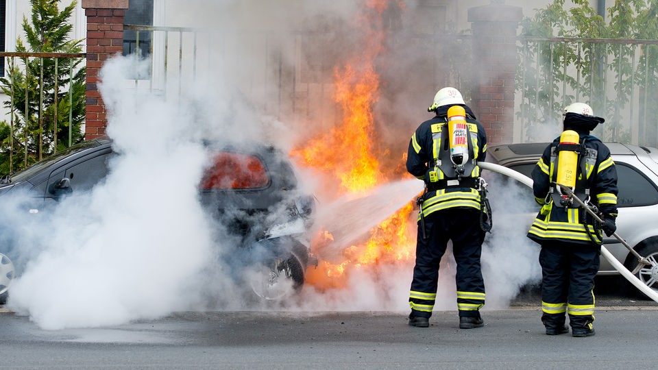 Feuerwehrmänner löschen brennende Autos.