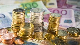 Euro-Münzen stapeln sich auf Euro-Scheinen.