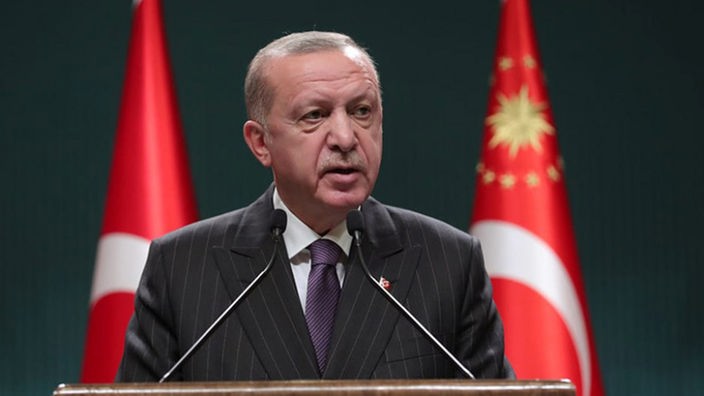 Präsident Erdogan bei einer Rede, hinter ihm zwei Türkei-Flaggen.