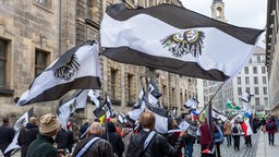 Teilnehmer einer Demonstration ziehen mit Flaggen vom Königreich Preußen (schwarz-weiß-schwarz mit Adler) durch die Dresdener Innenstadt. 