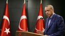 Recep Tayyip Erdogan bei einer Rede neben drei Türkeifahnen.
