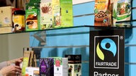 Fairtrade-Logo steht neben Fairtrade-Produkten in Regal.