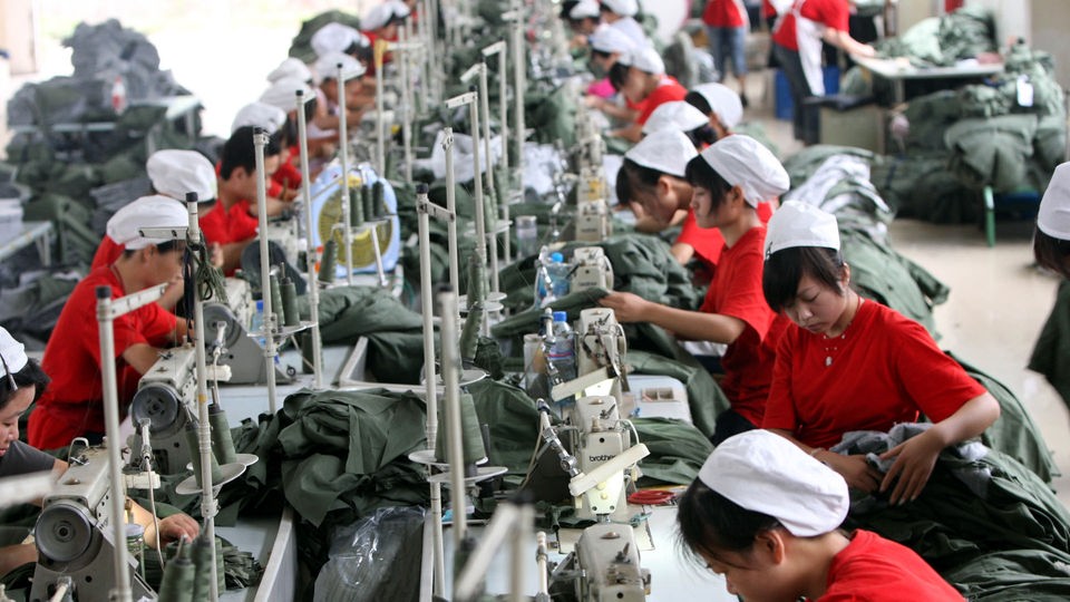 In einer Textilfabrik in China sitzen Näherinnen dicht an dicht vor ihren Nähmaschinen.